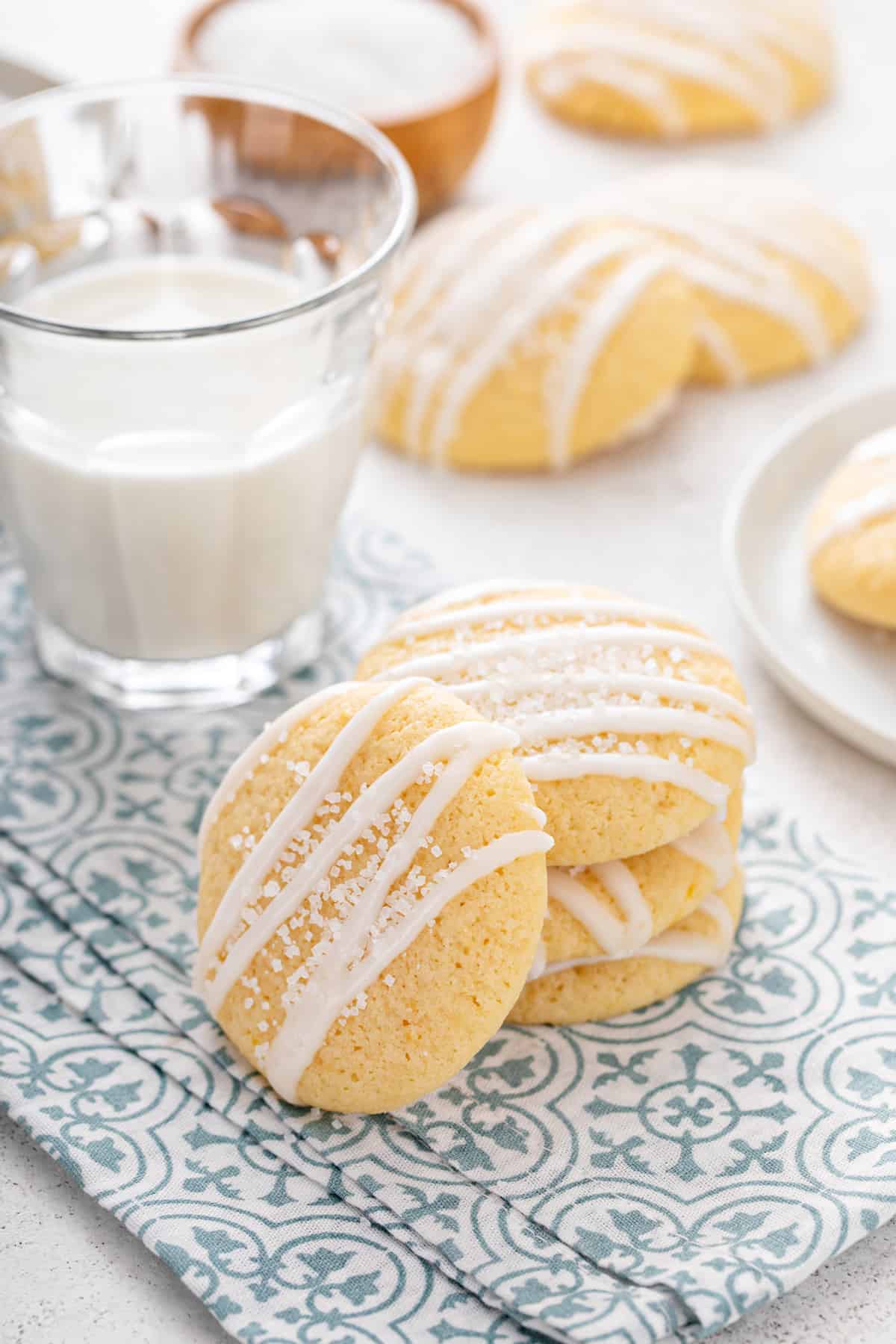 Three pound cake cookies stacked next to a glass of milk with a fourth cookie leaning against the stack.