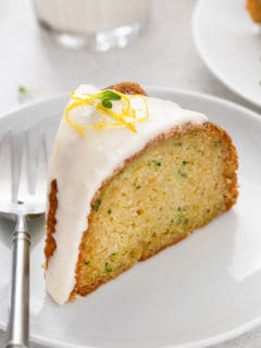 Slice of glazed lemon zucchini cake on a white plate.