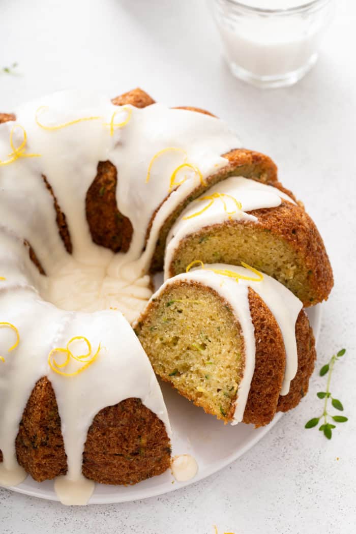 Sliced lemon zucchini bundt cake on a white cake plate.