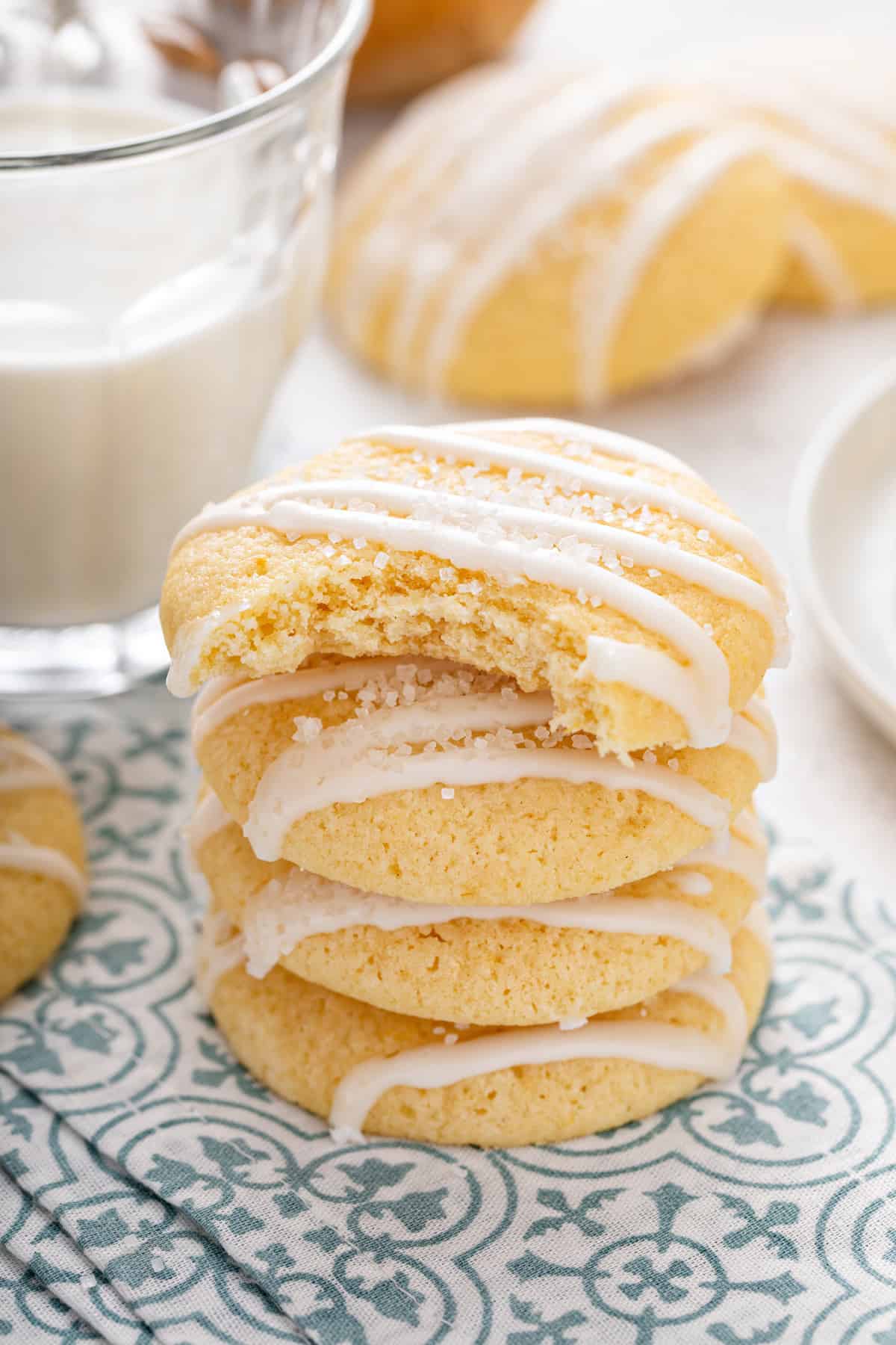 Stack of glazed pound cake cookies on a blue and white napkin. The top cookie has a bite taken from it.