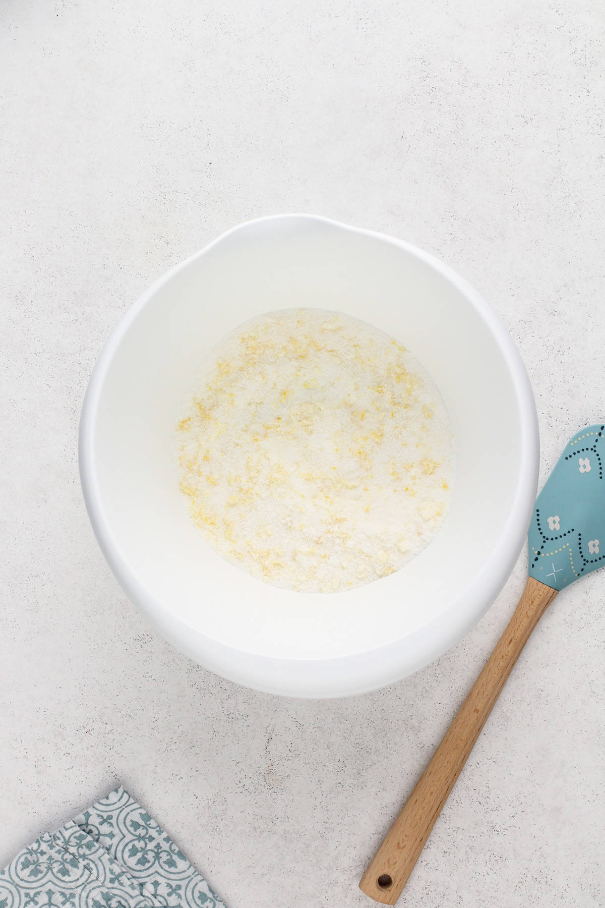 Sugar and lemon zest combined in a white mixing bowl.