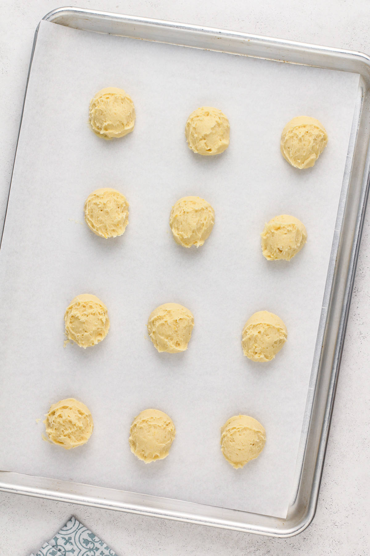 Unbaked pound cake cookies on a parchment-lined baking sheet, ready to go in the oven.