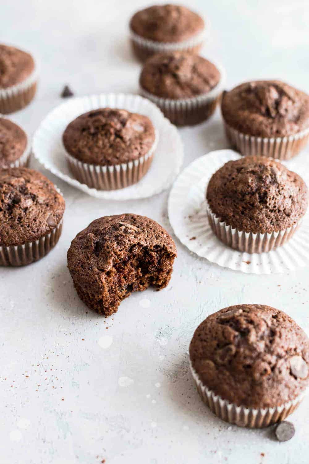 Half-eaten chocolate zucchini muffin surrounded by other chocolate muffins