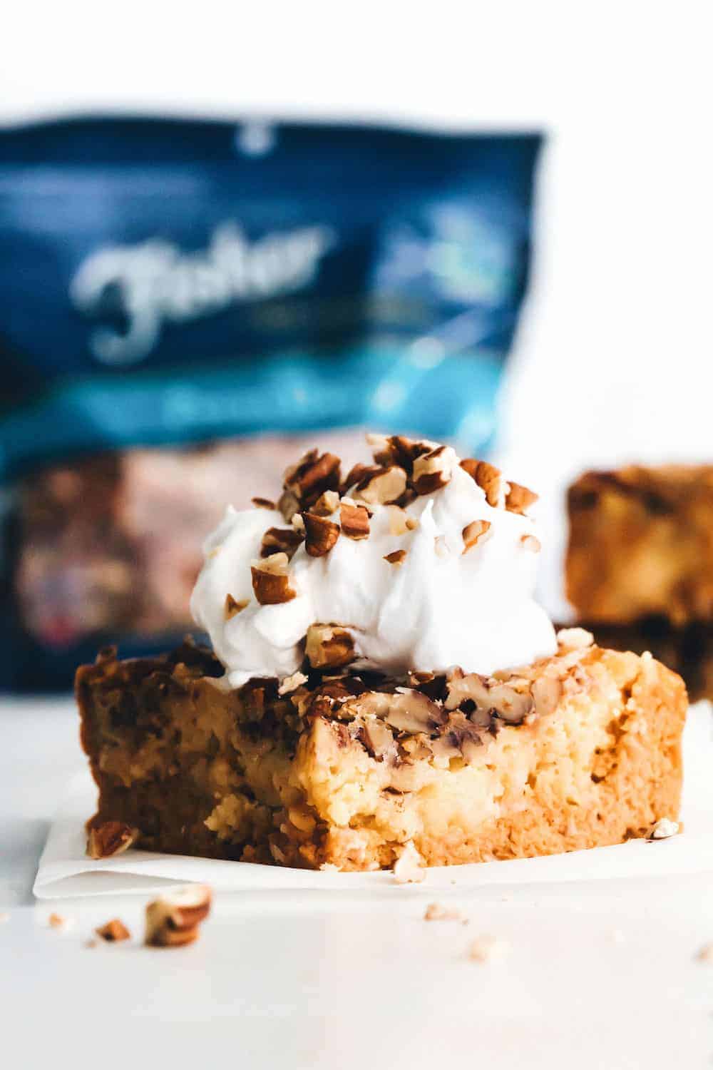 Piece of pumpkin crunch cake topped with whipped cream and sprinkled with chopped pecans