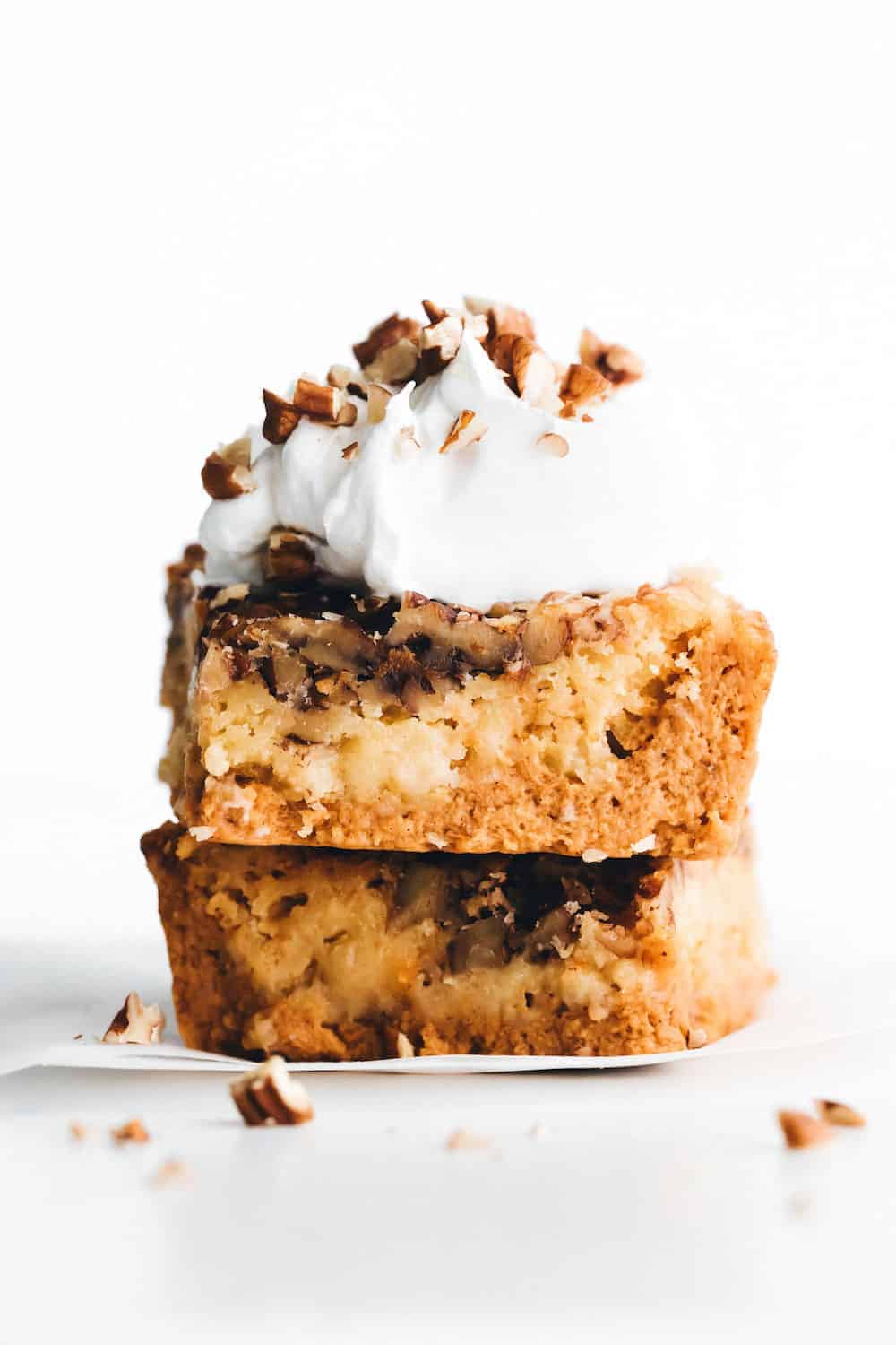 stacked pieces of pumpkin crunch cake with whipped cream and pecans