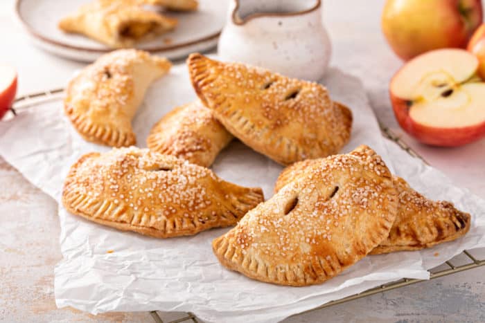 Several apple hand pies scattered in a piece of parchment paper.