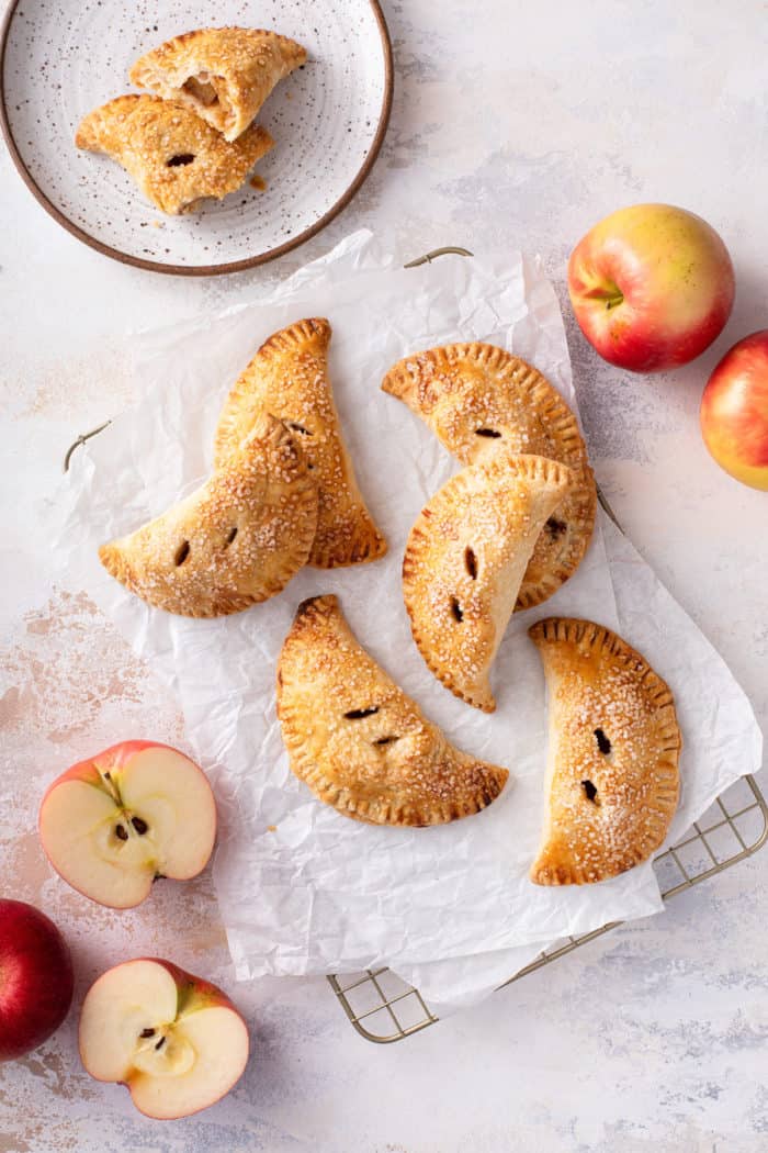 Overhead view of apple hand pies scattered on a piece of parchment paper.
