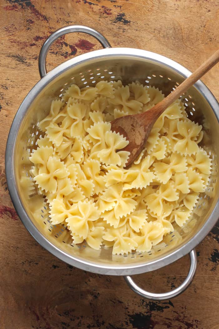 Cooked farfalle pasta in a metal strainer