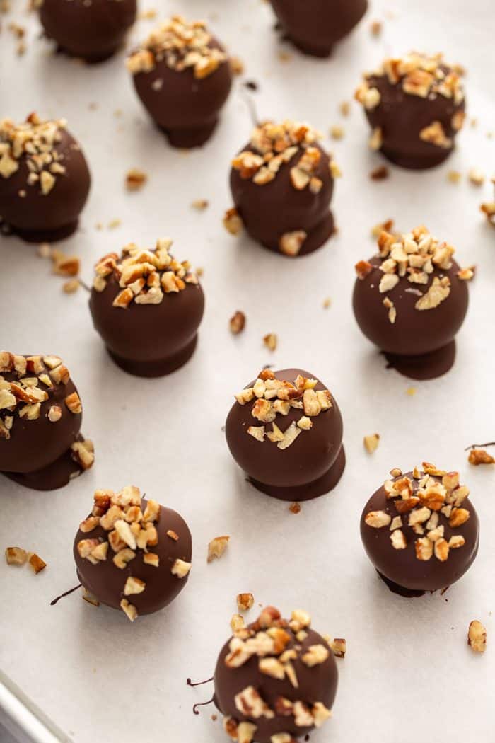 Decorated turtle cookie balls on a parchment-lined baking sheet