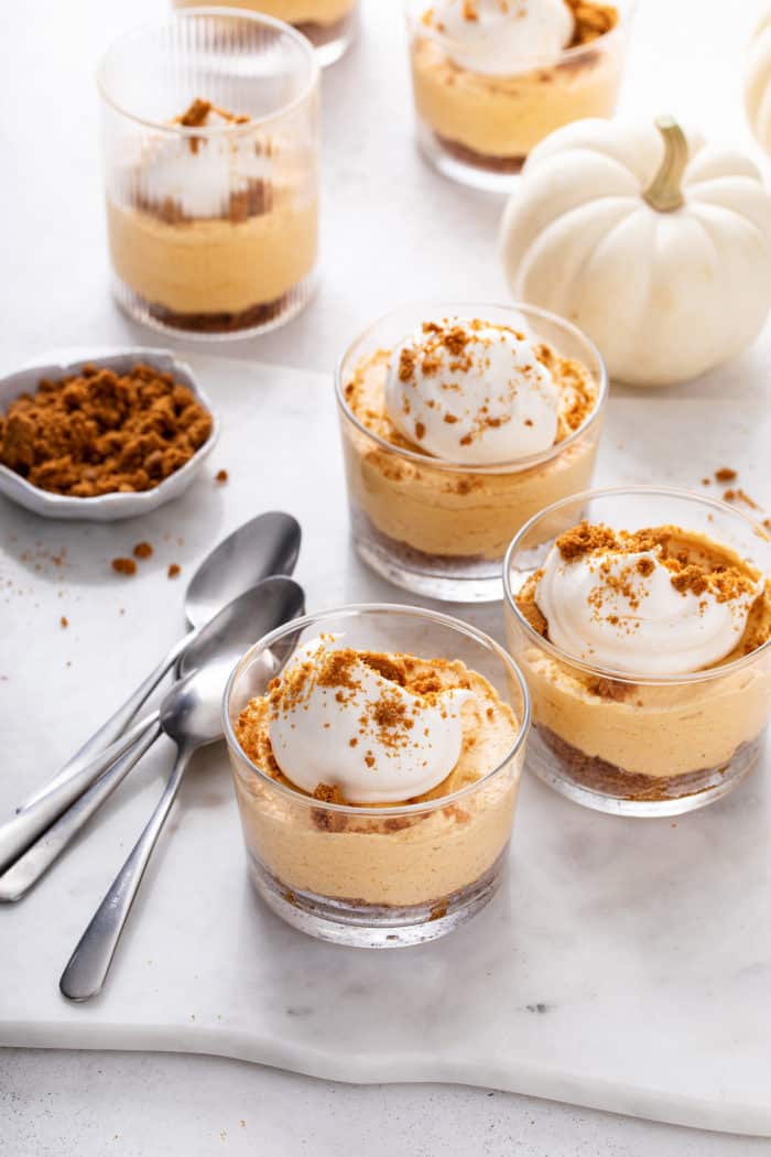 Several small glass dishes filled with no-bake pumpkin cheesecake on a marble surface.