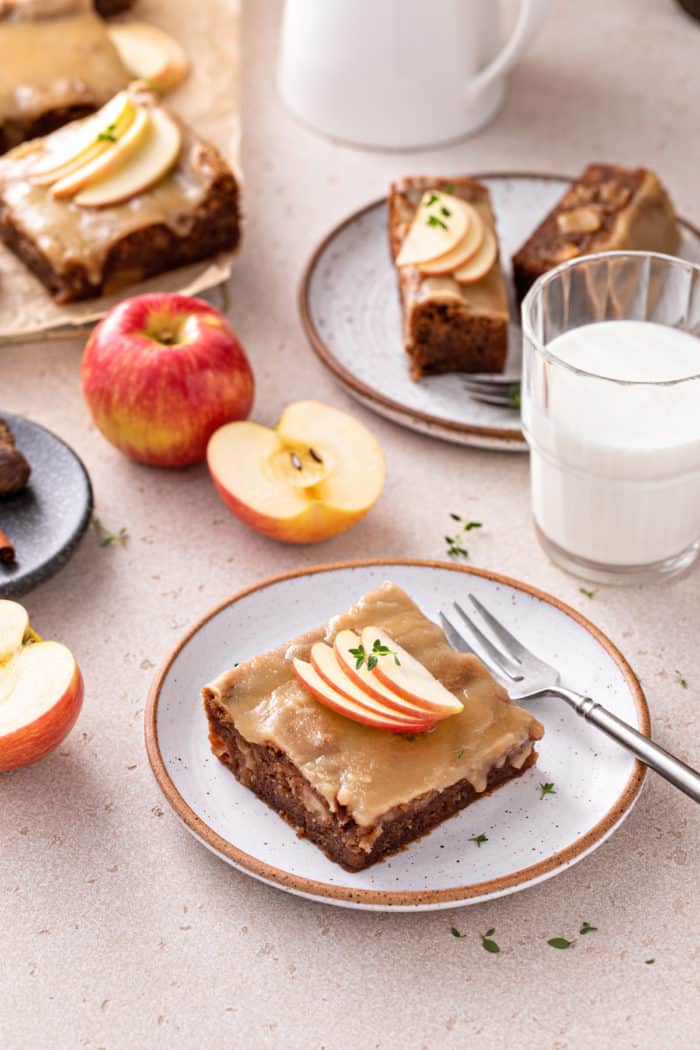 Slice of caramel apple cake garnished with thinly sliced apples set on a white plate.