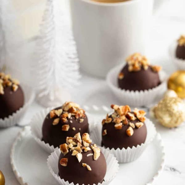 White plate with 3 turtle cookie balls in front of a cup of coffee