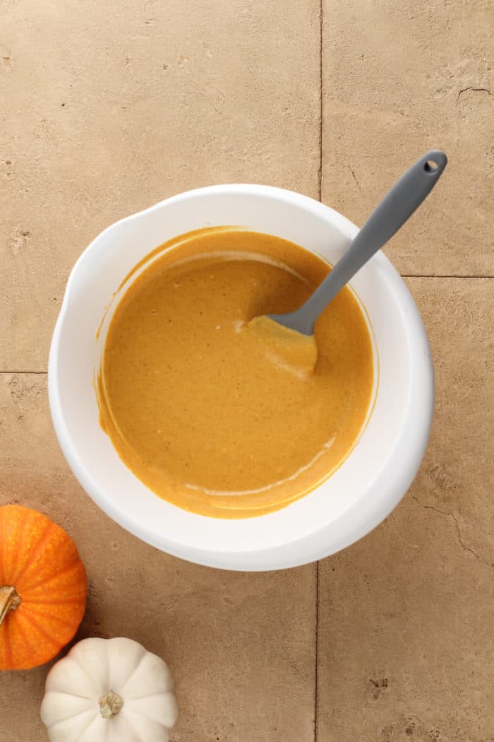 Pumpkin cheesecake filling in a white mixing bowl.