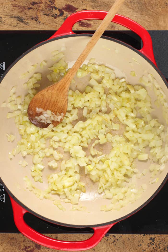 Onions sauteeing in a red dutch oven for lasagna soup