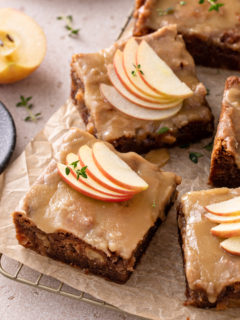 Slices of caramel apple cake, topped with salted caramel frosting and garnished with apple slices.
