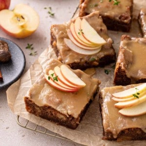 Slices of caramel apple cake, topped with salted caramel frosting and garnished with apple slices.