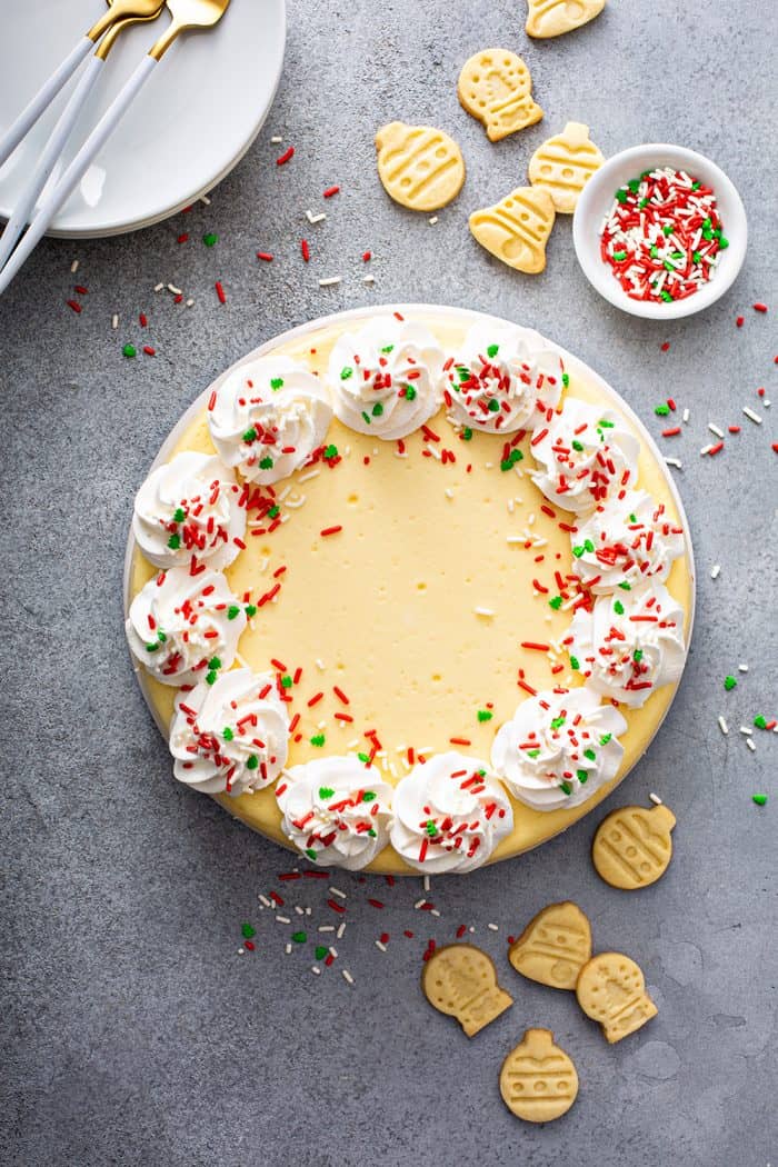 Overhead view of a sugar cookie cheesecake decorated with whipped cream and sprinkles