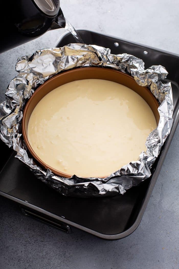 Water being poured into a water bath around a cheesecake