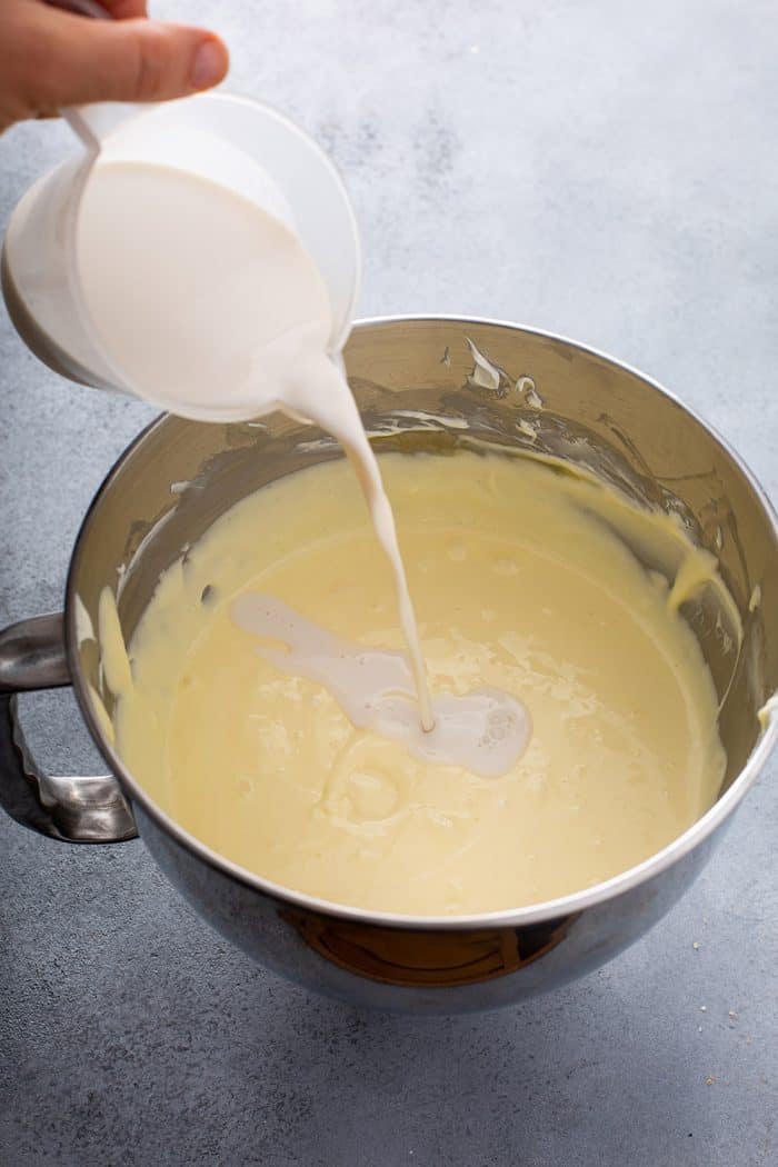 Creamer being added to cheesecake filling in a mixing bowl