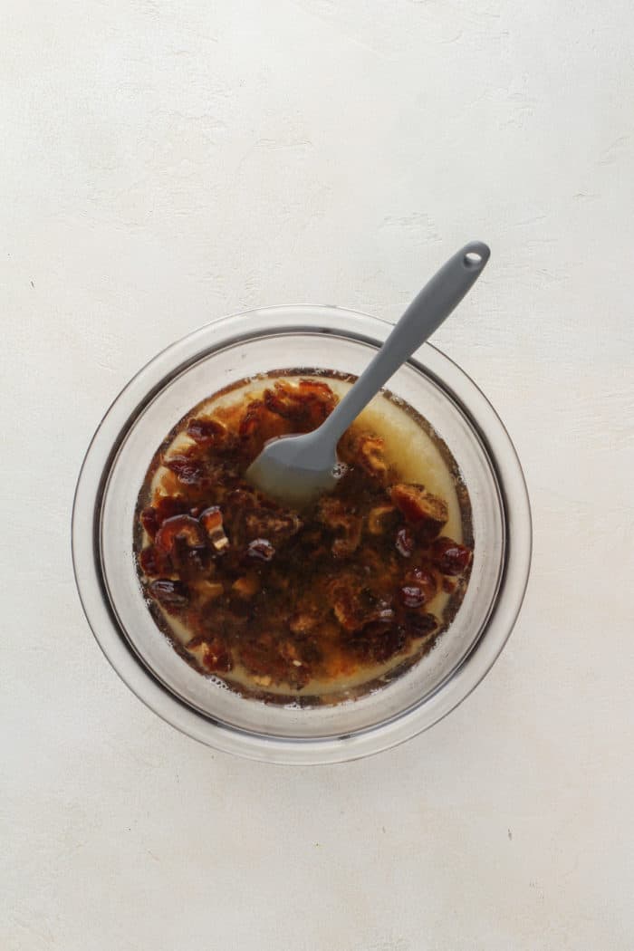 Dates soaked in water and baking soda in a glass mixing bowl.