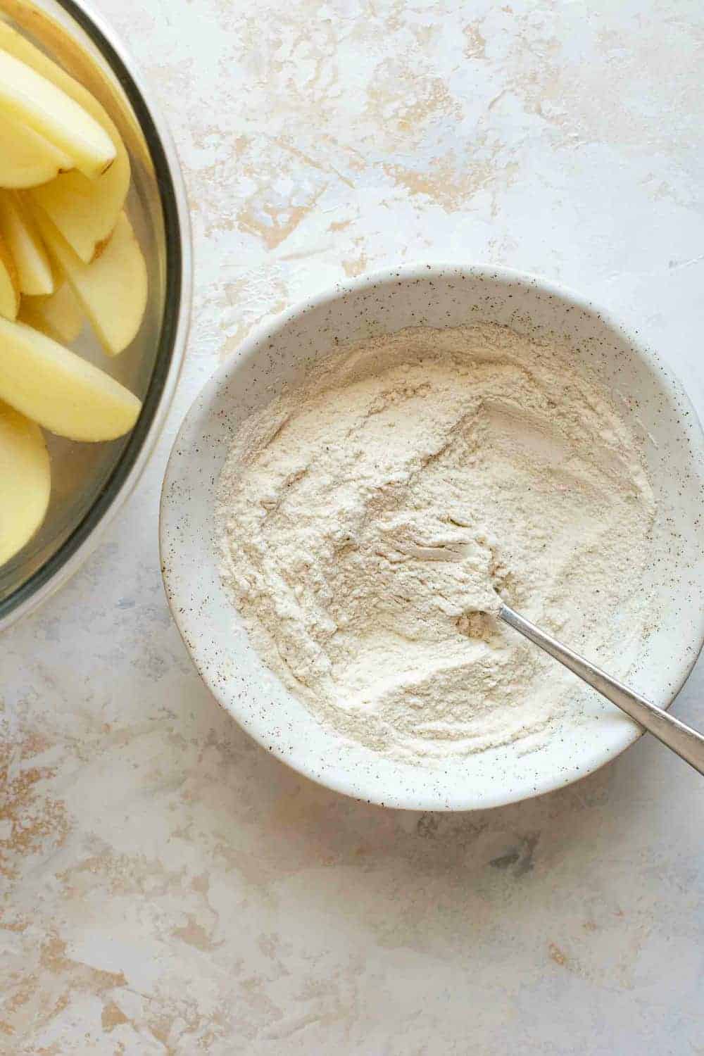 Seasoned flour ready to dredge cut potato wedges