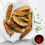 Jo Jo Potatoes on parchment paper next to a bowl of ketchup