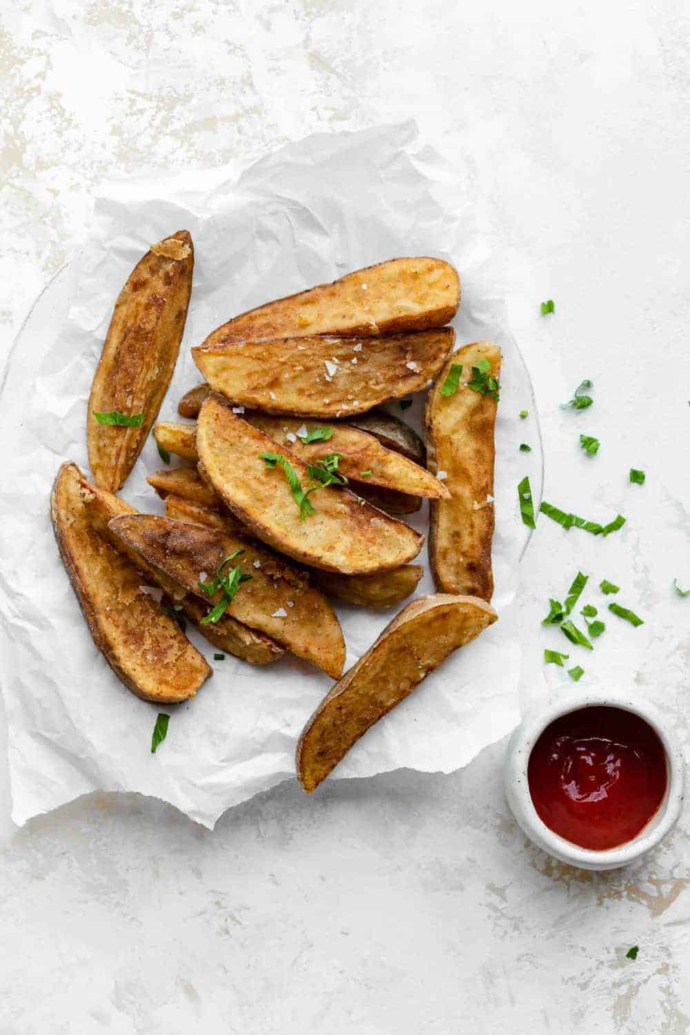 Jo Jo Potatoes on parchment paper next to a bowl of ketchup