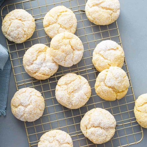 Gooey butter cookies scattered on a metal cooling rack on a gray counter