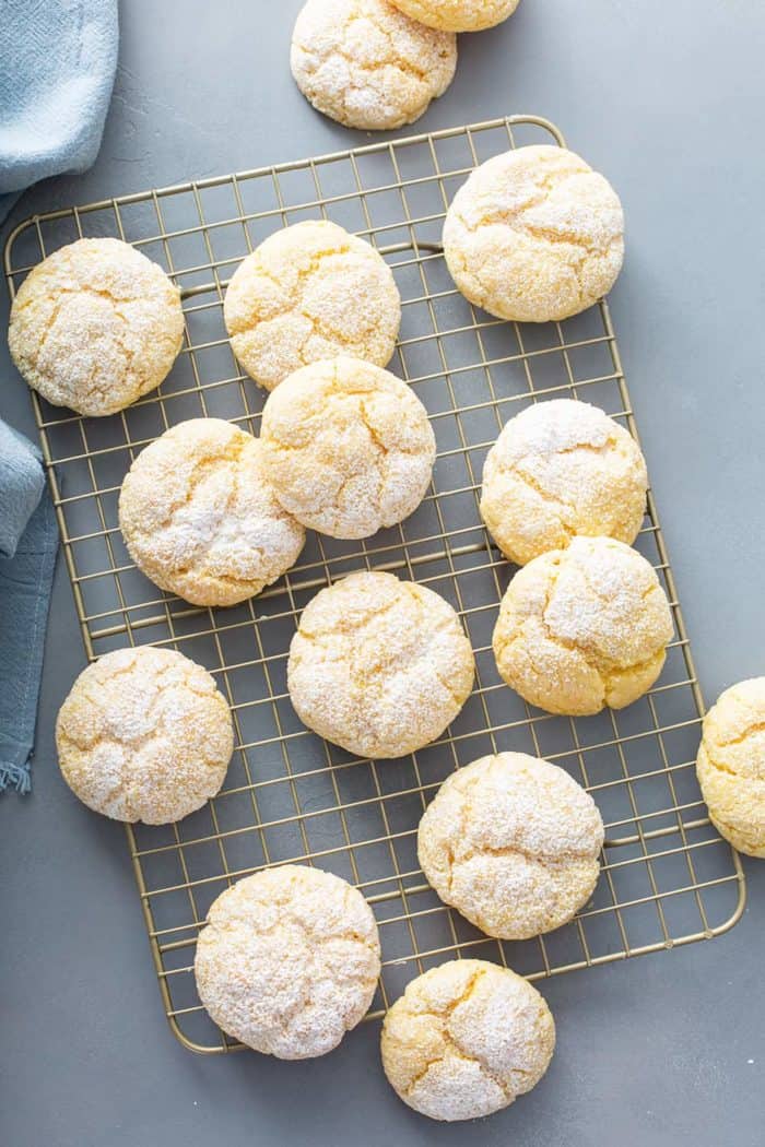 Gooey butter cookies scattered on a metal cooling rack on a gray counter