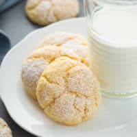 Three gooey butter cookies arranged next to a glass of milk on a white plate
