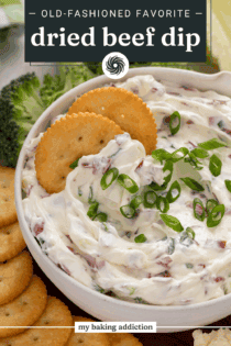 Two crackers nestled into a bowl of dried beef dip. Text overlay includes recipe name.