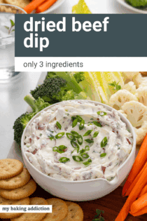 Bowl of dried beef dip on a board surrounded by fresh veggies and crackers. Text overlay includes recipe name.