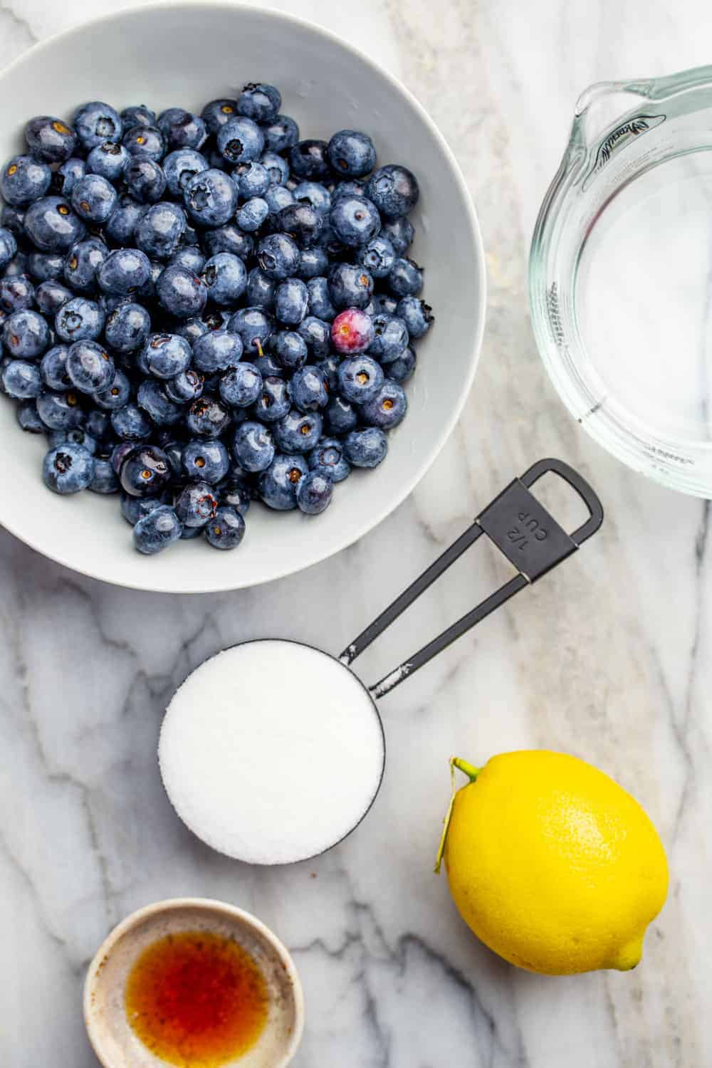 Ingredients for homemade blueberry sauce on a marble surface