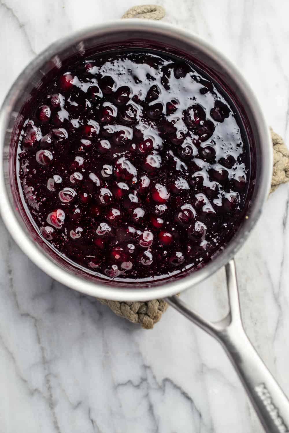 Freshly made homemade blueberry sauce in a saucepan on a marble surface