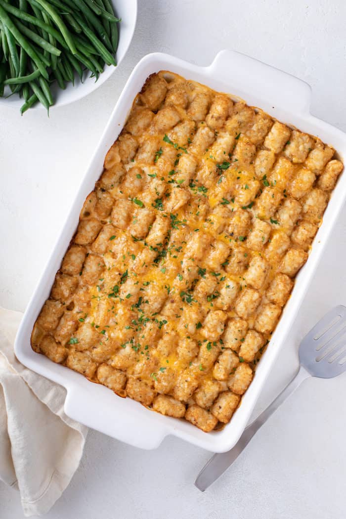 Overhead view of baked cheeseburger tater tot casserole in a white baking dish