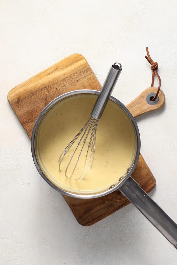 Cheese sauce in a saucepot being stirred with a whisk