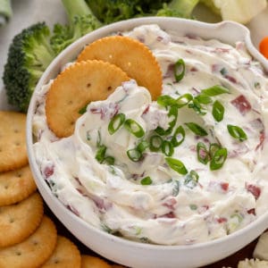 Bowl of dried beef dip with two crackers in it.