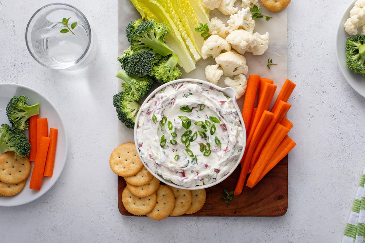 Overhead view of a bowl of dried beef dip on a veggie platter with crackers.
