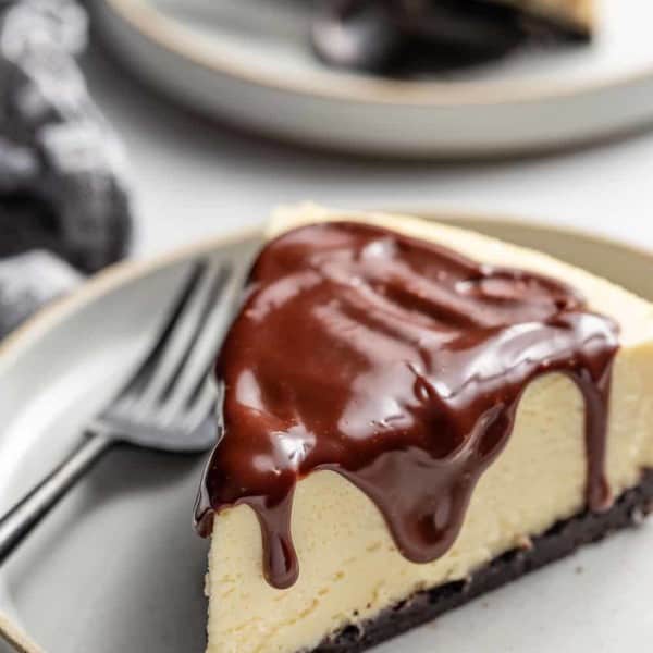 Slice of Baileys cheesecake next to a fork on a gray plate