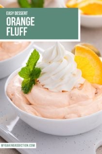 Close up of orange fluff in a white bowl, garnished with whipped cream and an orange slice. Text overlay includes recipe name.
