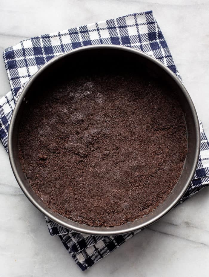 Oreo cookie crust pressed into the bottom of a springform pan on a marble countertop