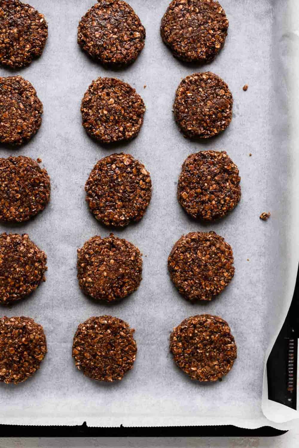 Flatted no bake cookies on a parchment-lined cookie sheet