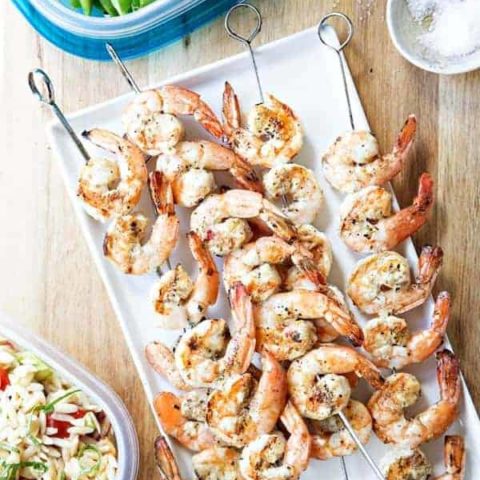 Plate full of grilled basil shrimp on skewers ready to enjoy