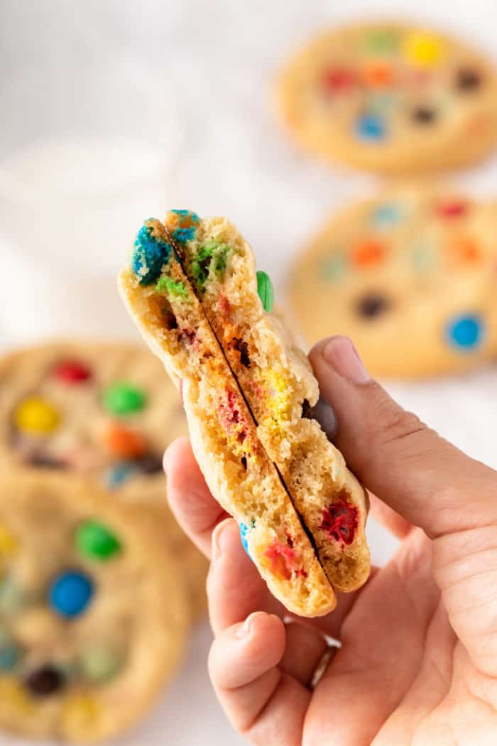 M&M cookie broken in half and being held up to the camera.