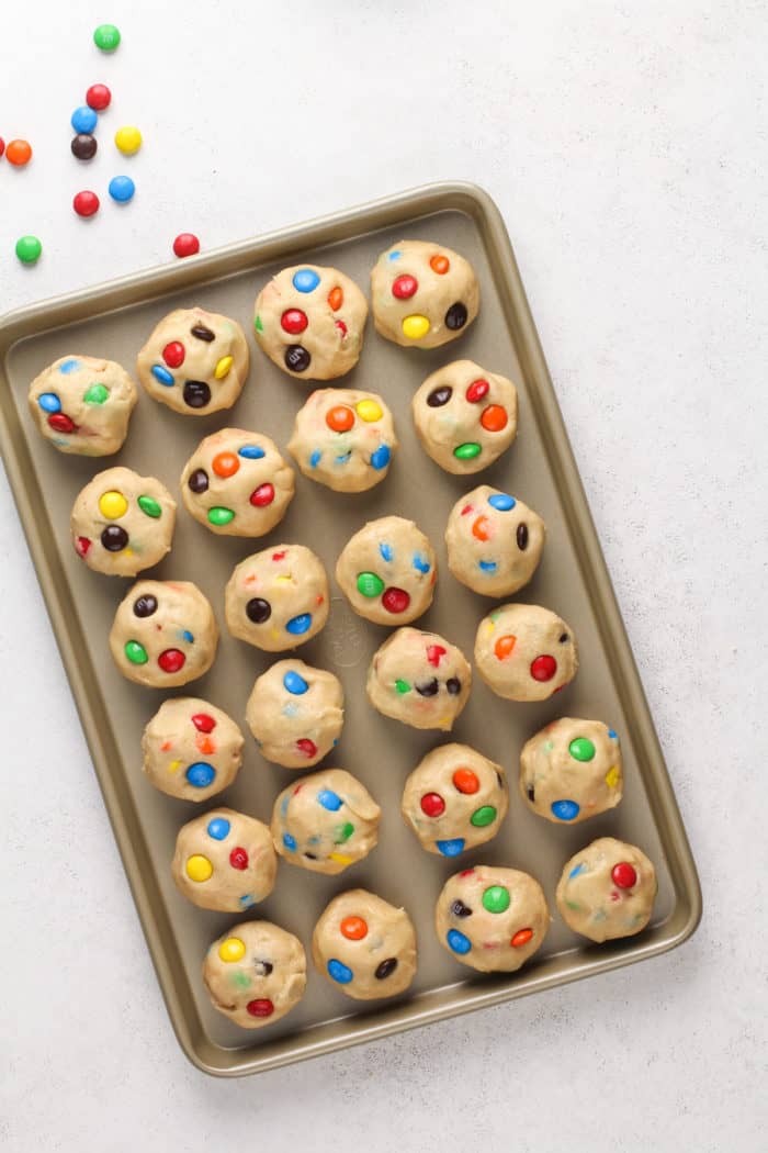 Balls of m&m cookie dough set on a baking sheet to chill.