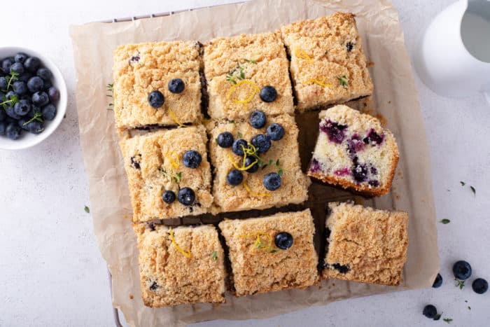 Overhead shot of a sliced blueberry coffee cake set on a piece of parchment paper.