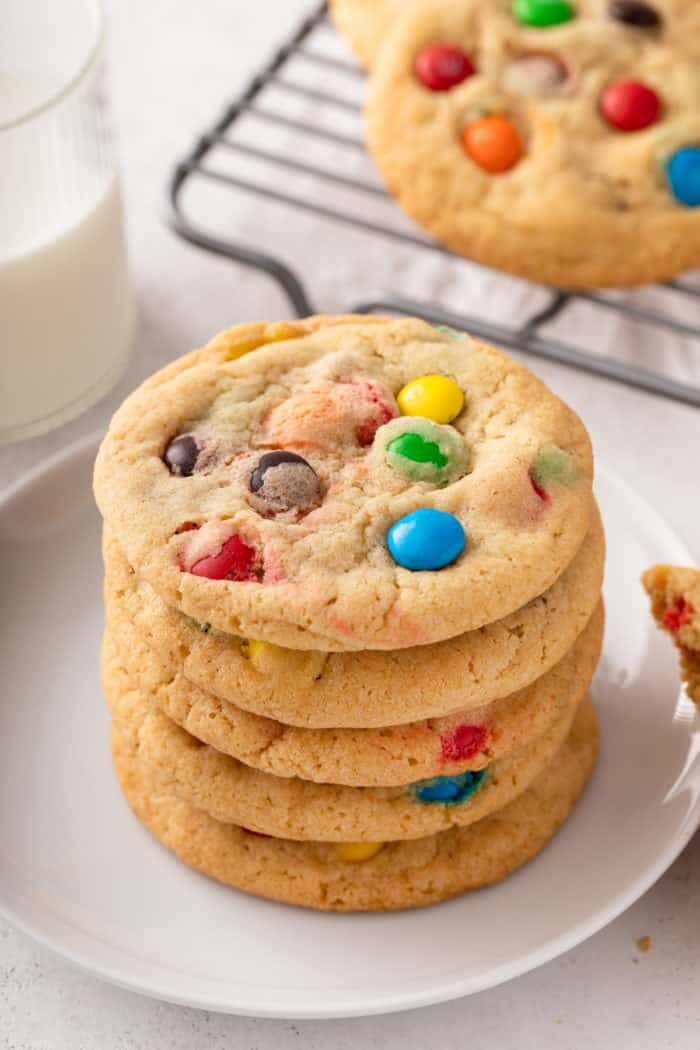 5 m&M cookies stacked on a white plate.