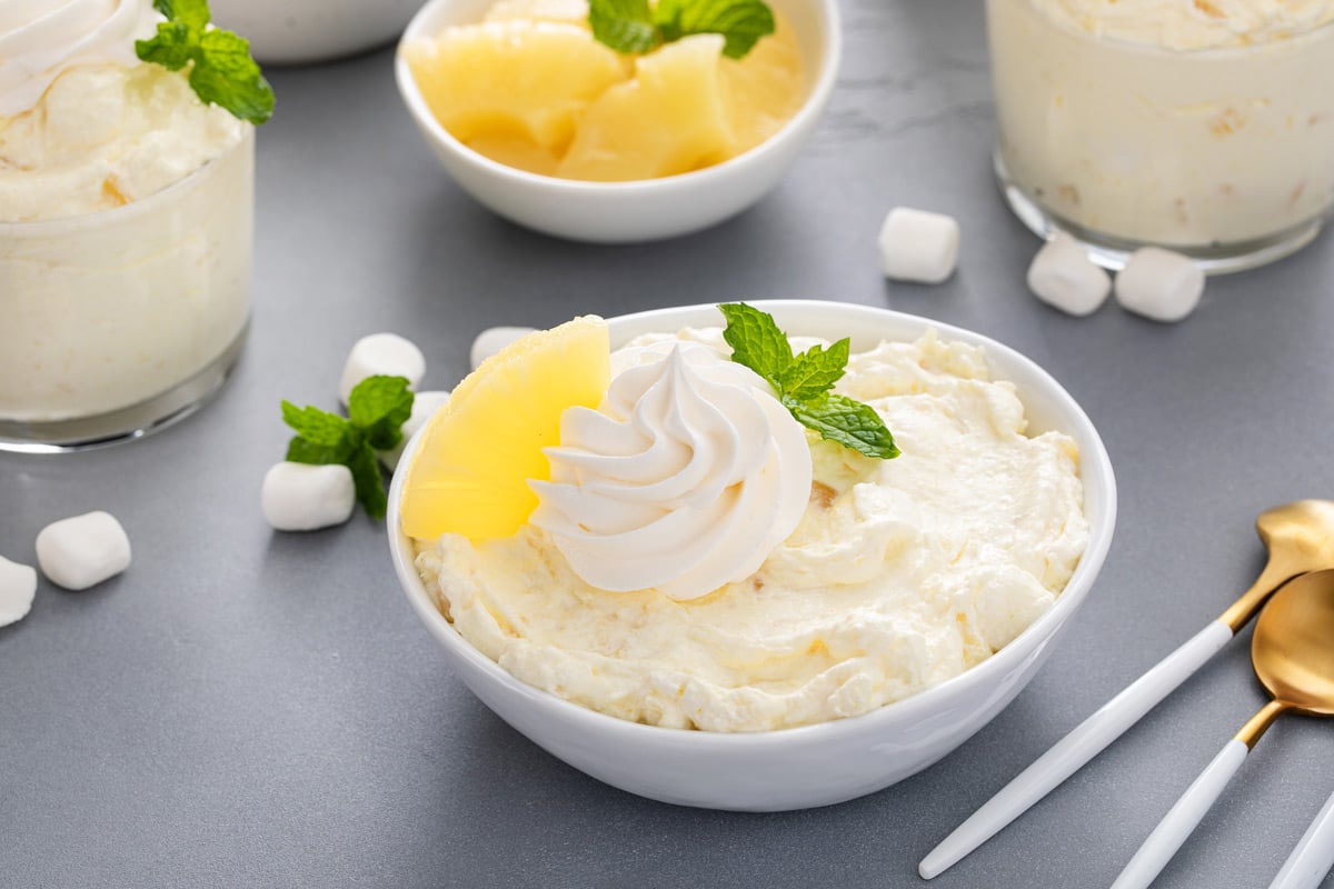 Shallow white bowl of pineapple fluff on a gray countertop.