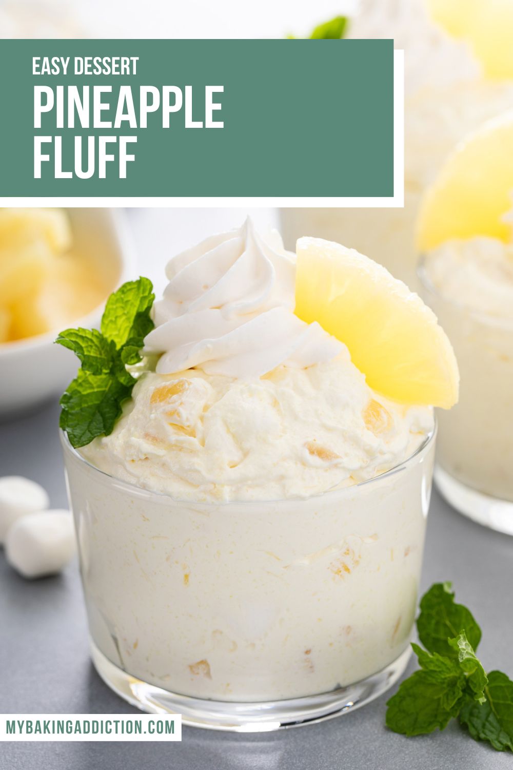 Closeup image of a glass cup filled with pineapple fluff and topped with whipped topping and pineapple. Text overlay includes recipe name.