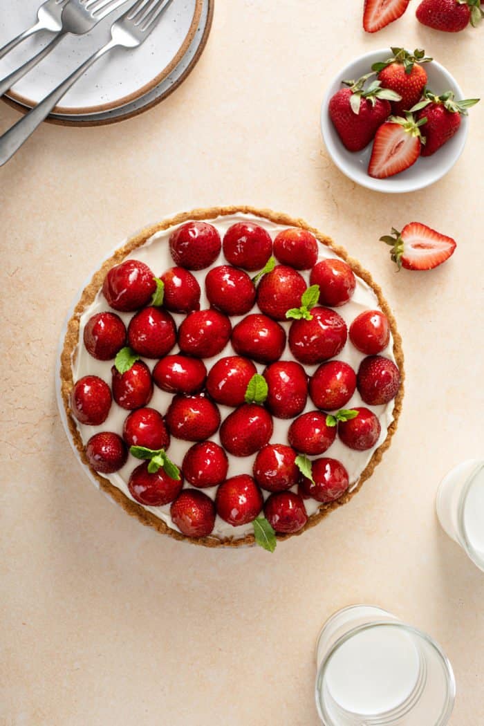 Overhead view of a strawberry tart garnished with sprigs of mint.